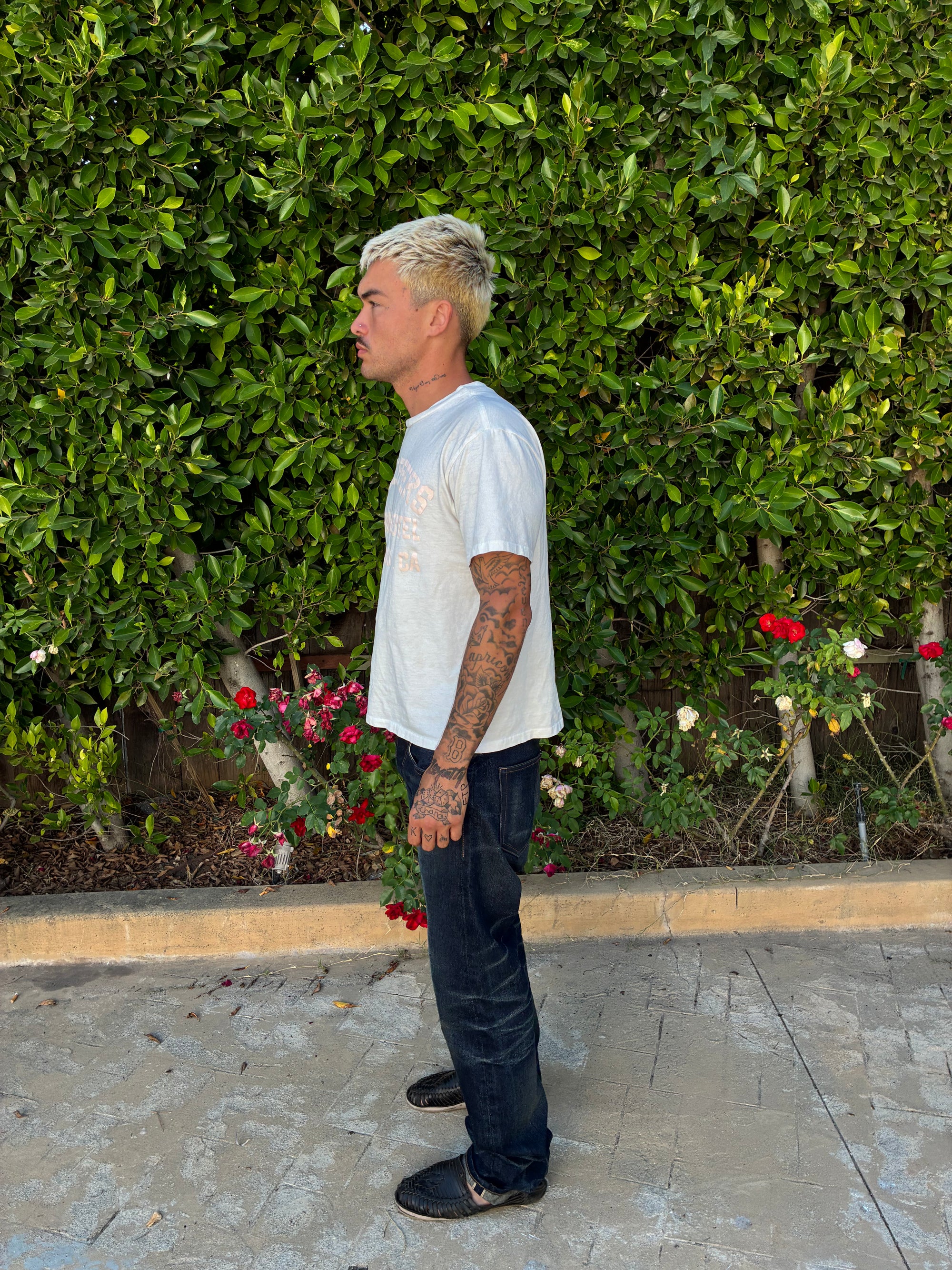 Side view of a model wearing the pink print tee tucked into dark jeans