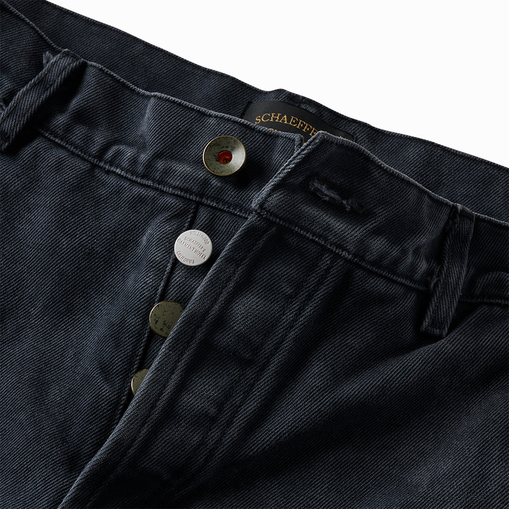 Close-up of the black shorts' waistband with silver button fly and Schaeffer's label
