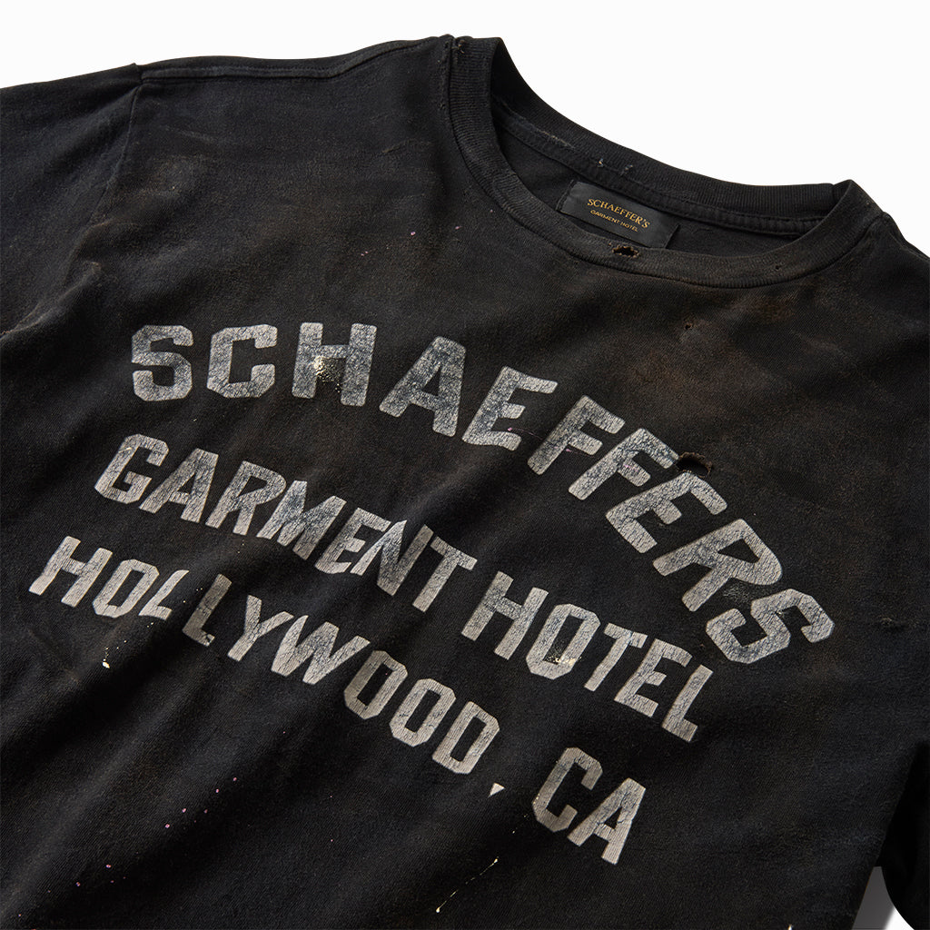 Close-up of the cracked white varsity lettering on the black tee