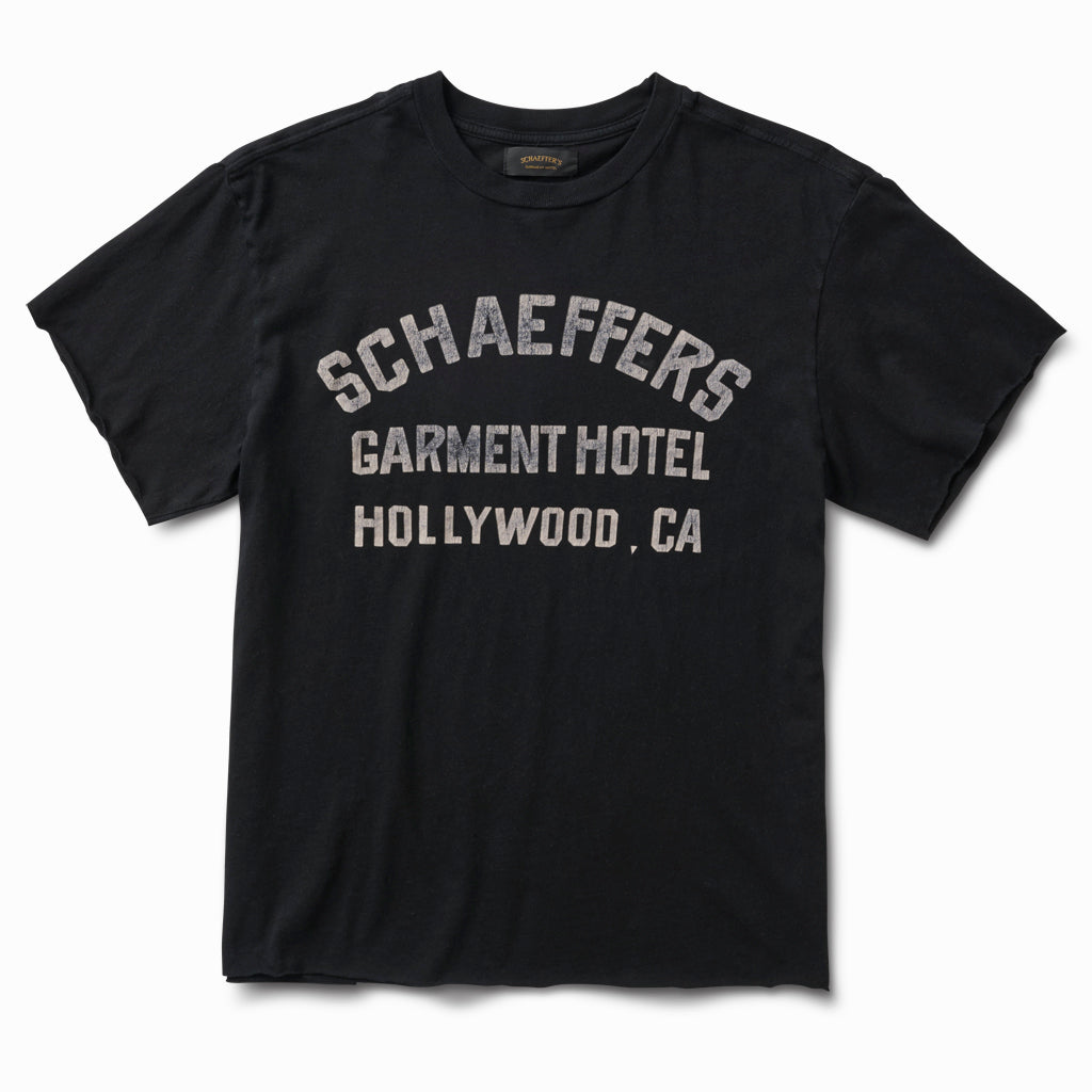 Black raw cut tee with a white Schaeffers Garment Hotel Hollywood, CA varsity print, front view