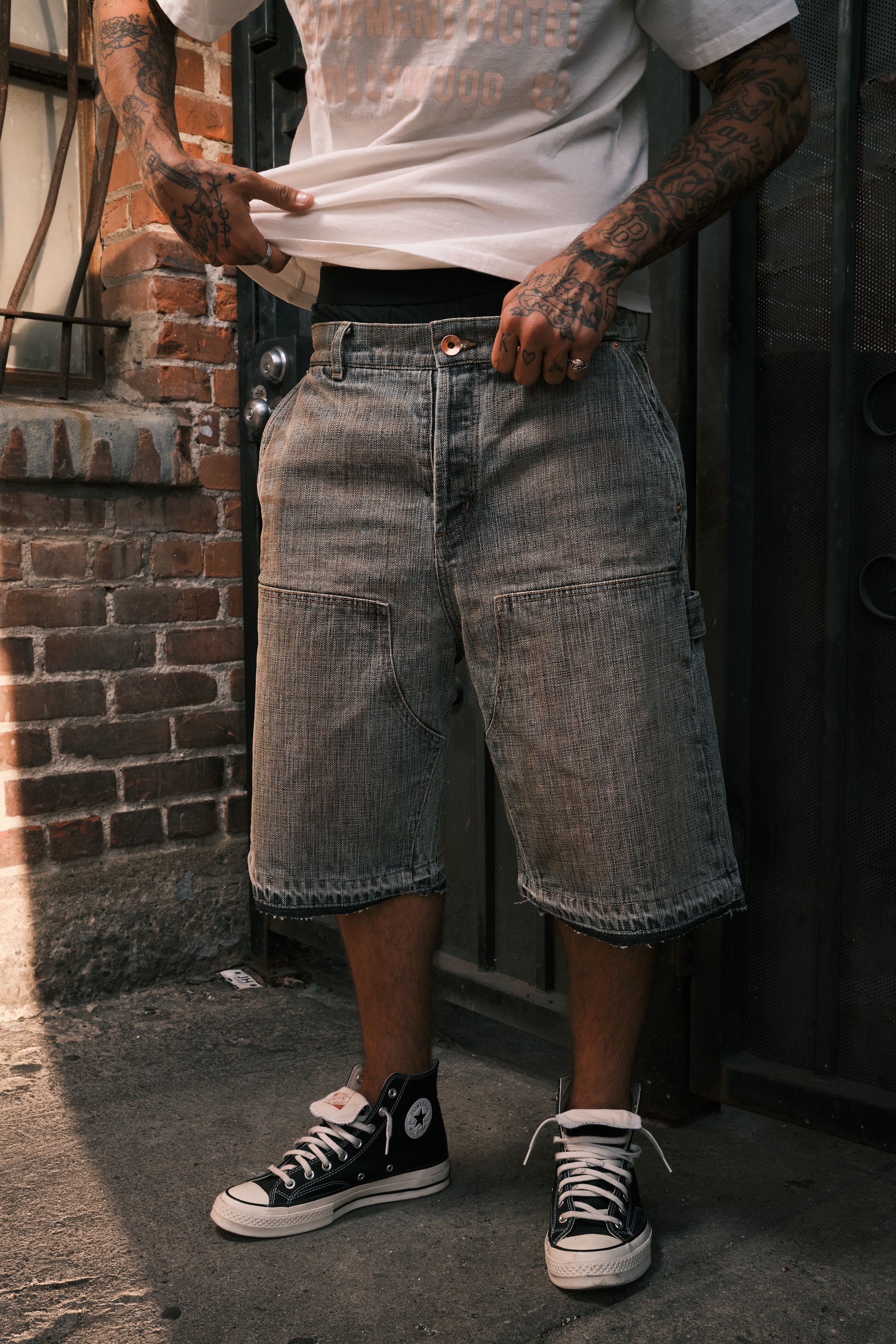 Front view of the faded indigo shorts worn with a white tee and black high-top sneakers
