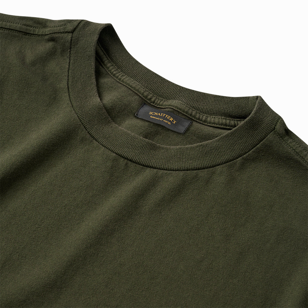 Close-up of the green tee's ribbed collar and Schaeffer's neck label