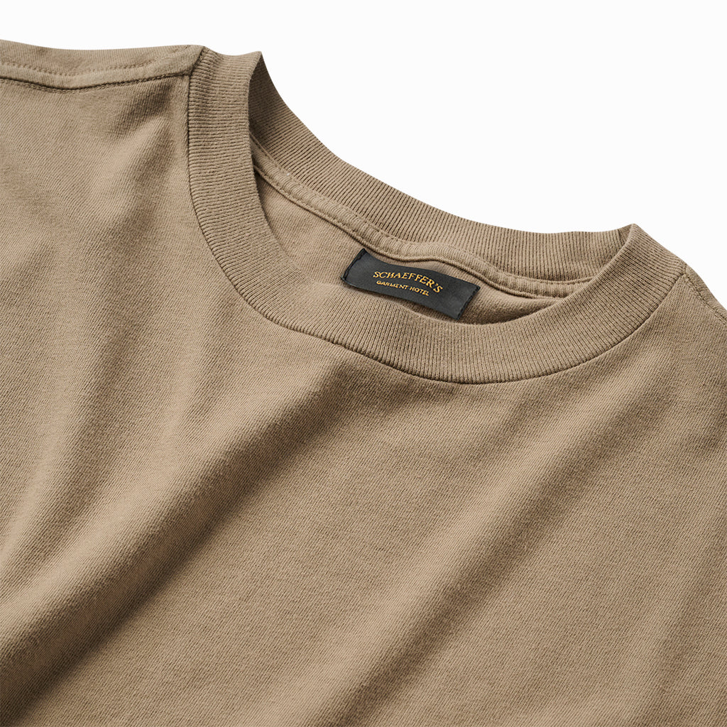 Close-up of the tan tee's ribbed collar and Schaeffer's neck label