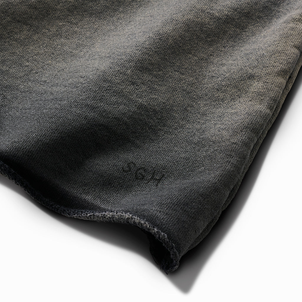 Close-up of the raw hem with small SGH embroidery on the oil-stained crew