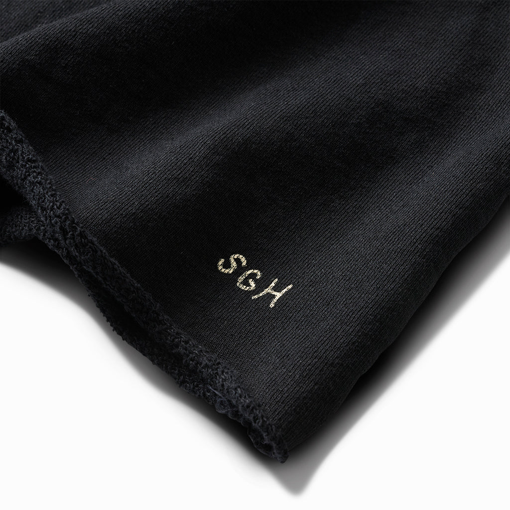 Close-up of the ivory SGH embroidery on the black crew's raw hem