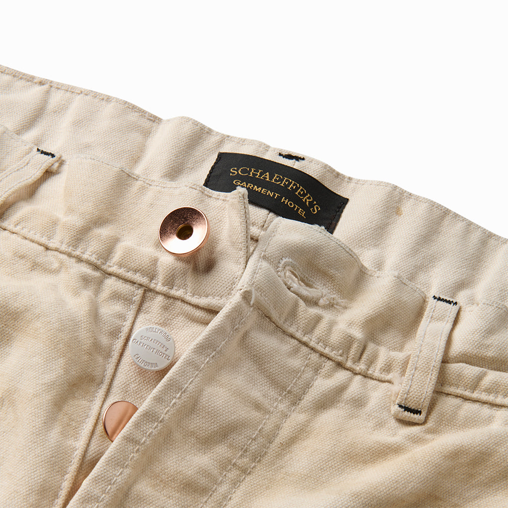 Close-up of the white carpenter pant's copper and silver button fly and Schaeffer's label