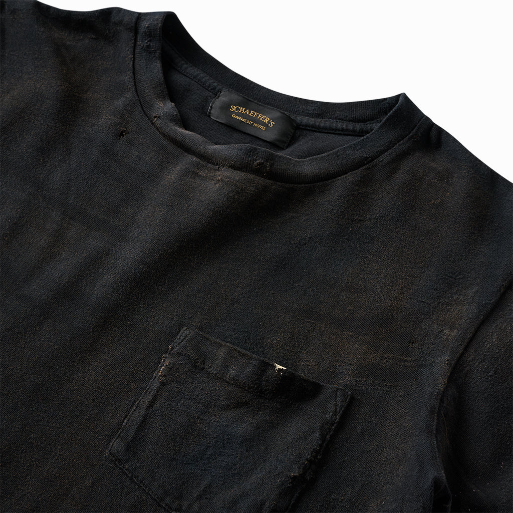 Close-up of the worn black tee's collar label and chest pocket