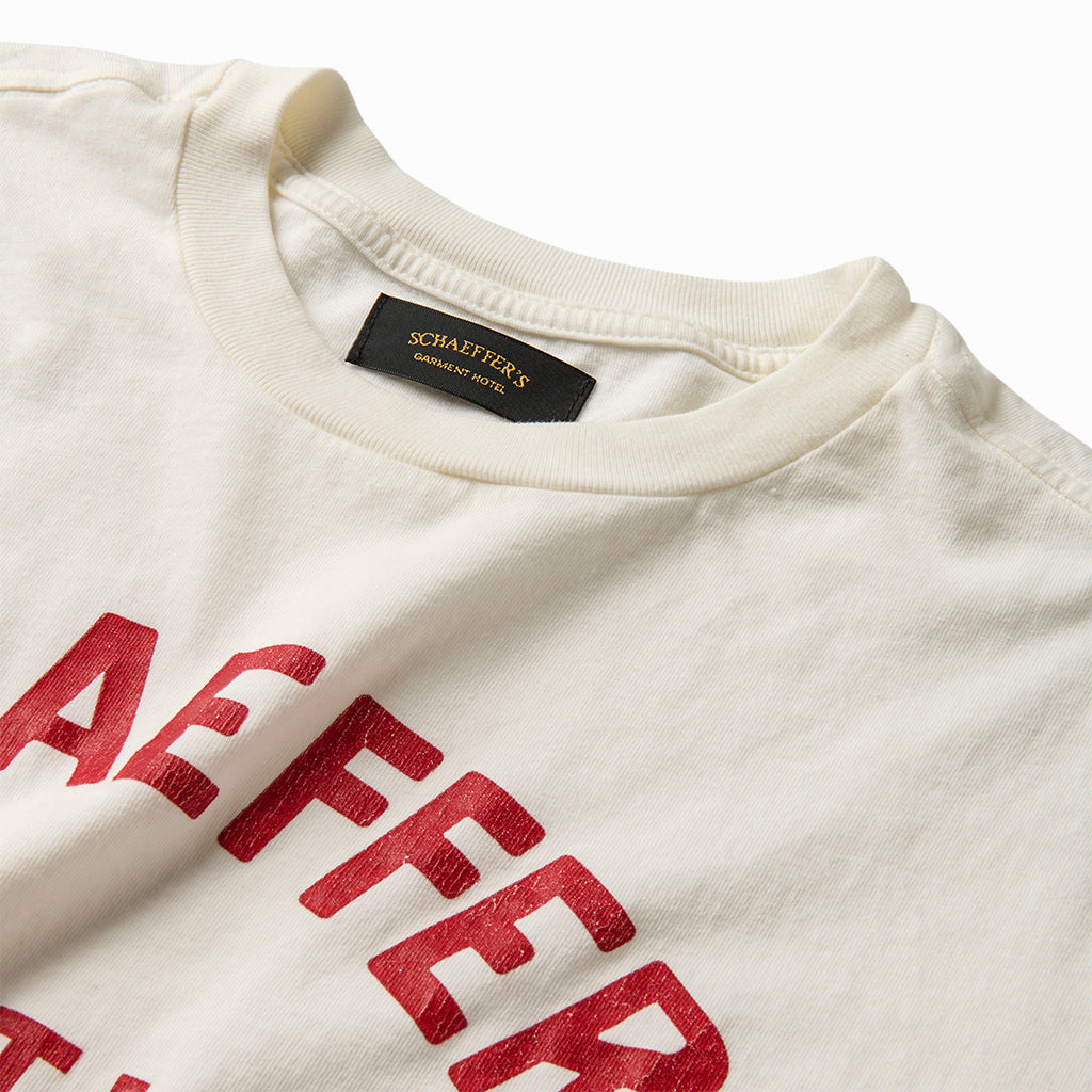 Close-up of the red varsity lettering and collar label on the off-white tee