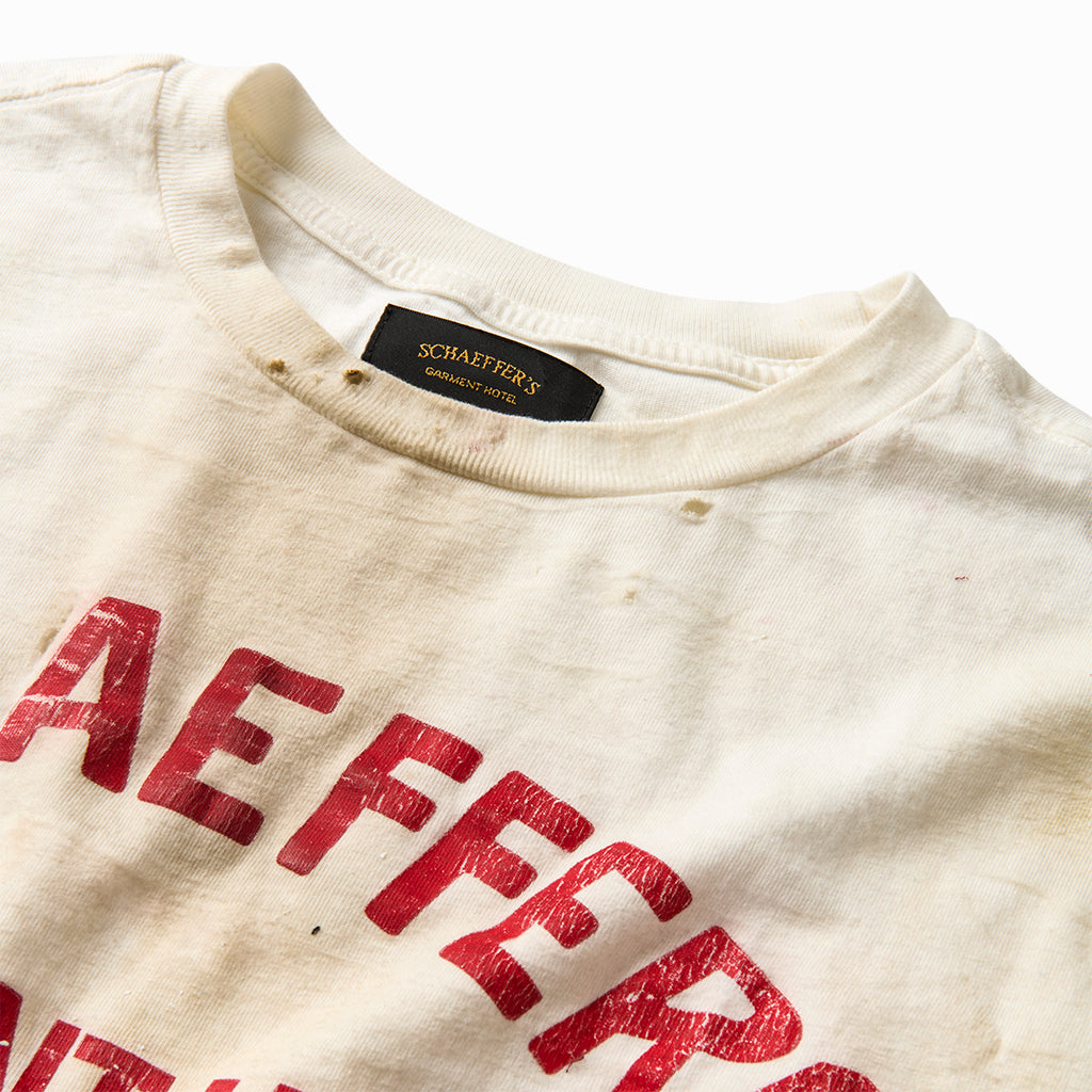 Close-up of the red varsity lettering and pinhole-distressed collar on the stained tee