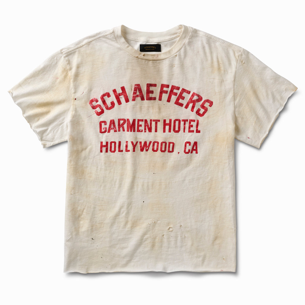 Distressed off-white raw cut tee with a red Schaeffers Garment Hotel Hollywood, CA varsity print and aged staining