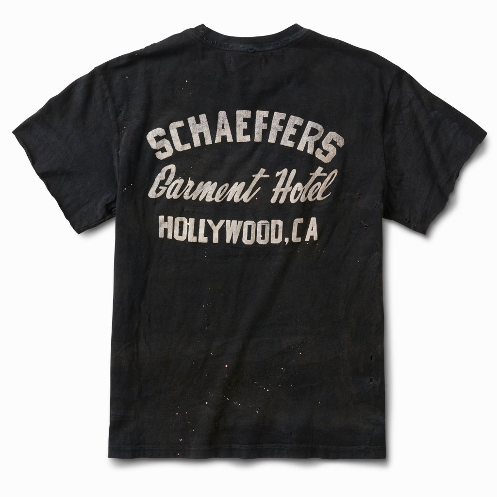 Distressed black tee, back view, with a white Schaeffers Garment Hotel Hollywood, CA script print