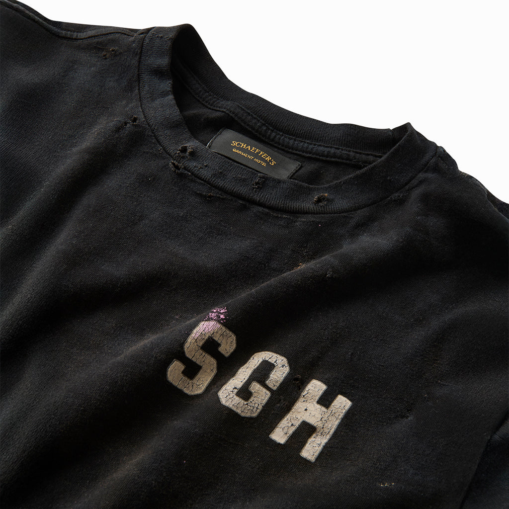 Close-up of the worn SGH chest print and frayed collar on the distressed black tee