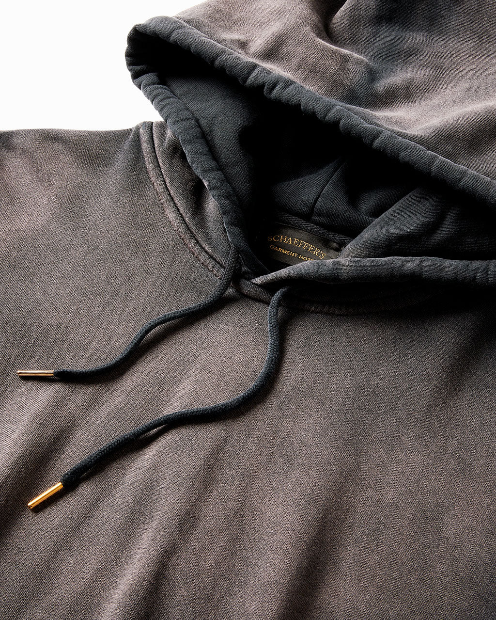 Close-up of the faded black hoodie's hood and drawcords with brass tips