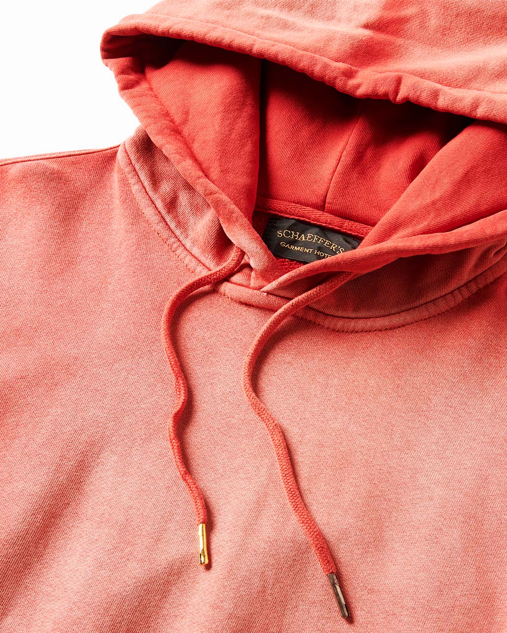 Close-up of the red hoodie's hood, drawcords with brass tips and neck label