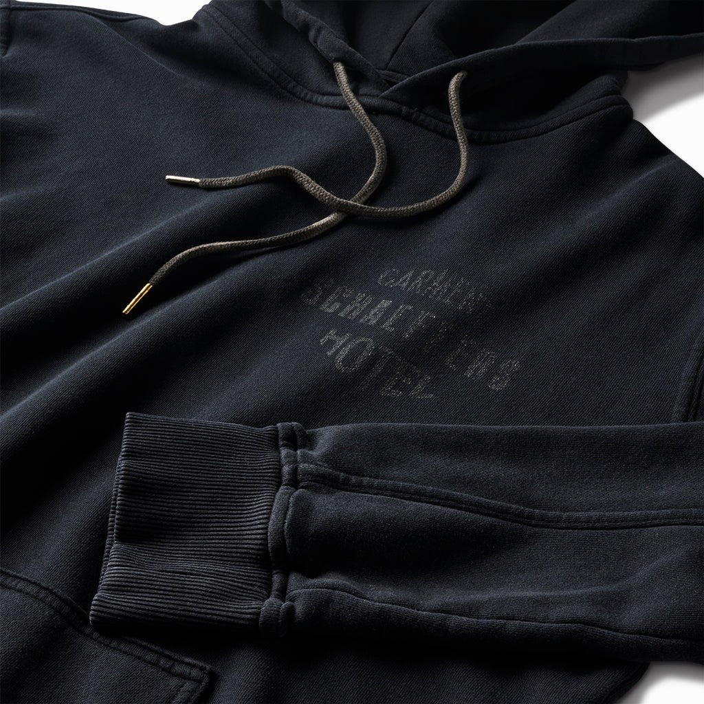 Close-up of the tonal Schaeffer's Garment Hotel chest print, drawcords and ribbed cuff
