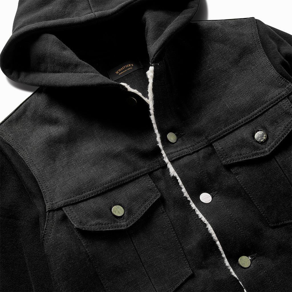 Close-up of the black hooded denim jacket's snap buttons, chest pockets and shearling edge