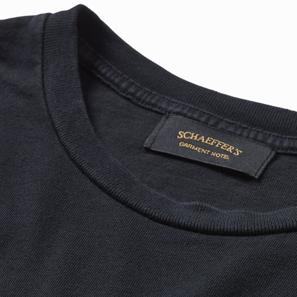 Close-up of the worn black pocket tee's collar and Schaeffer's Garment Hotel neck label