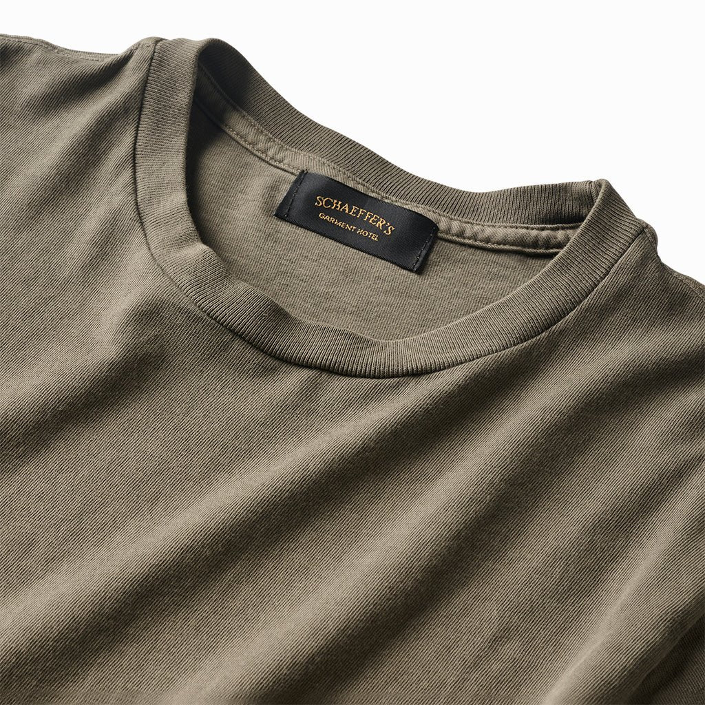 Close-up of the moss green tee's ribbed collar and Schaeffer's neck label