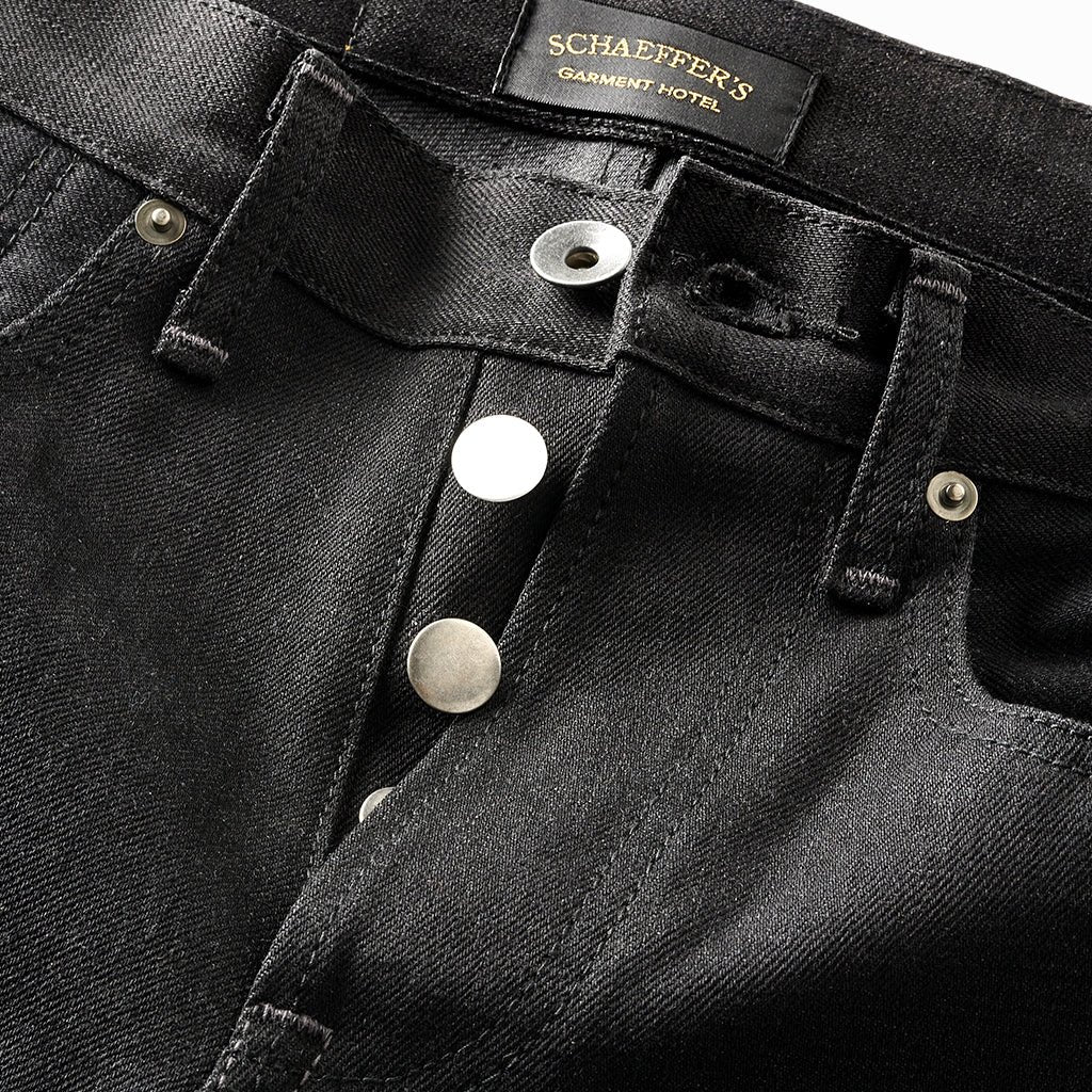 Close-up of the black denim shorts' silver button fly and Schaeffer's Garment Hotel label