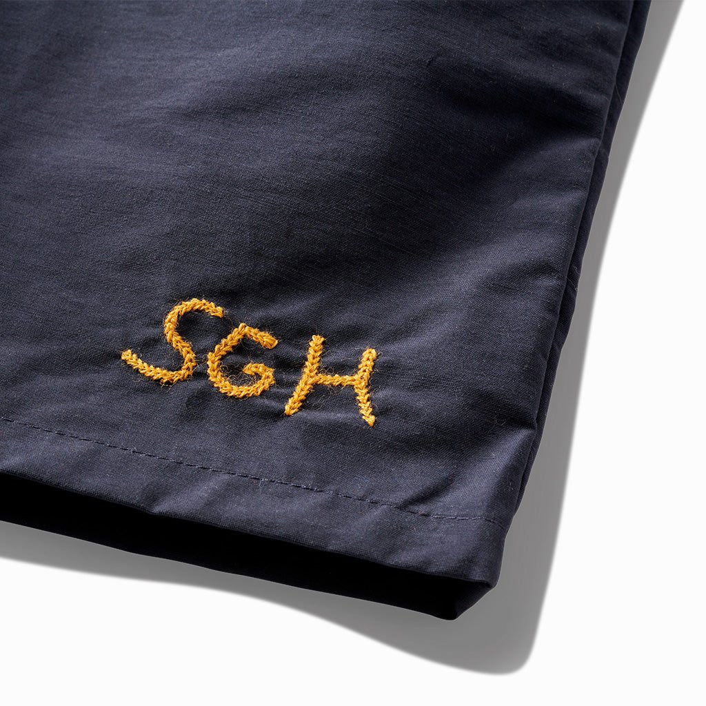 Close-up of the gold SGH embroidery on the indigo trunks' leg
