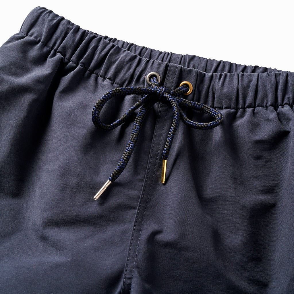 Close-up of the indigo trunks' elastic waist and navy drawcord with brass tips