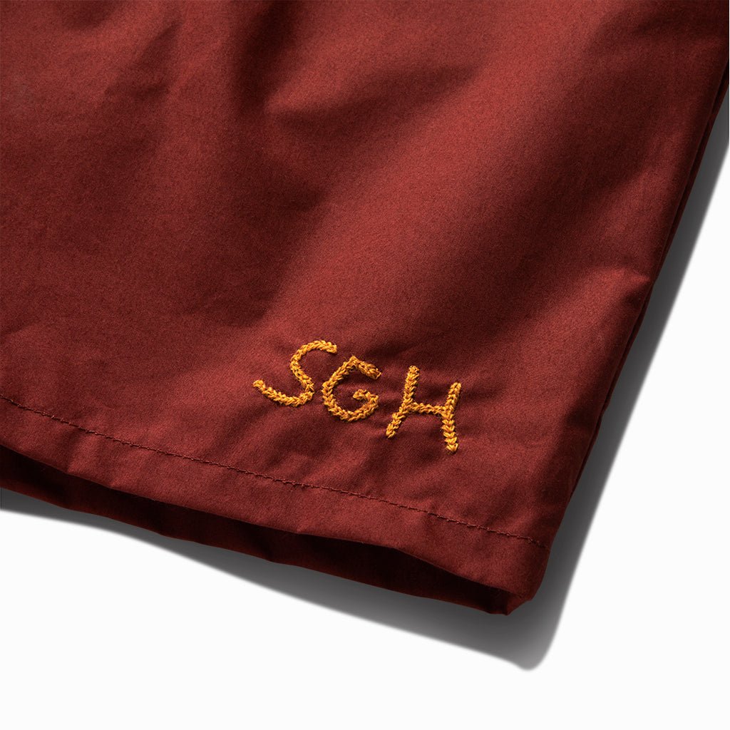 Close-up of the gold SGH embroidery on the ox blood trunks' leg