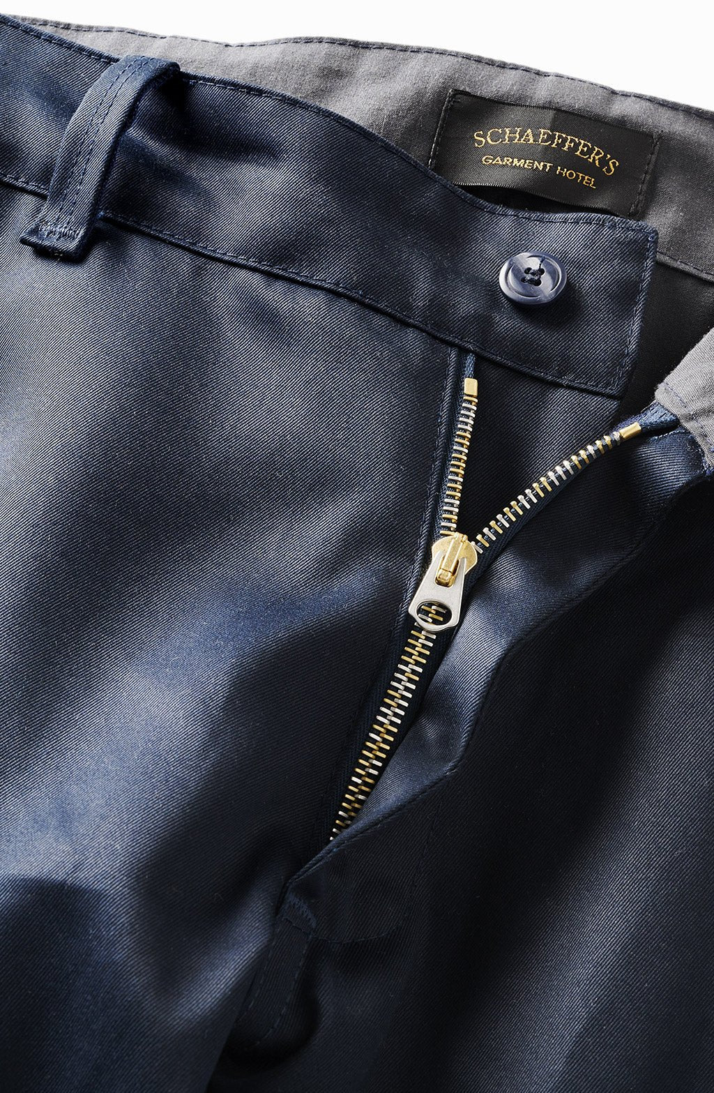 Close-up of the waxed indigo chino's brass zip fly, button and Schaeffer's label